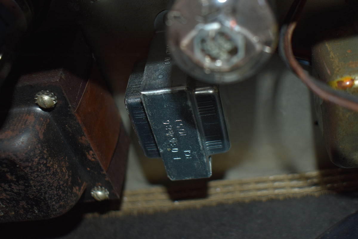 A close-up of the amplifier's interior shows a black tube socket with visible numbers, a large brown transformer, and a glowing vacuum tube.