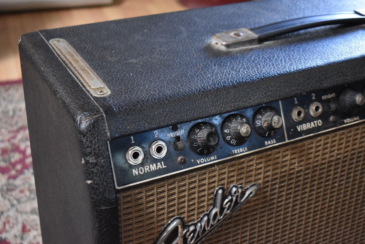 The black tolex amp shows wear and tear, with a rusty handle and control panel, and a brown grille cloth.