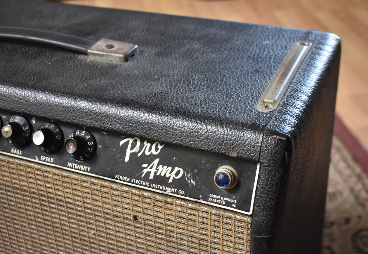 Close-up of the black tolex amp's top and front, showing the handle, three black control knobs, a blue jewel light, and brown grille cloth.