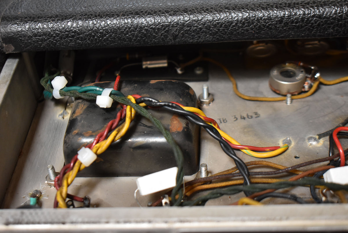 Close-up of the amplifier's internal wiring, showing a black transformer, colorful wires bundled with white ties, and a metal chassis.