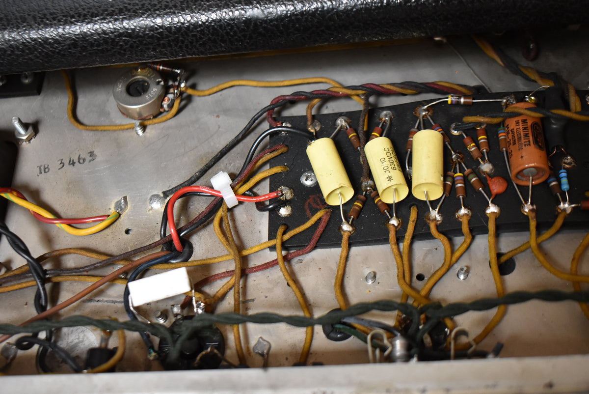 Close-up of the amp's internal wiring, showing a silver chassis with hand-soldered components, cloth-covered wires, and yellow capacitors.