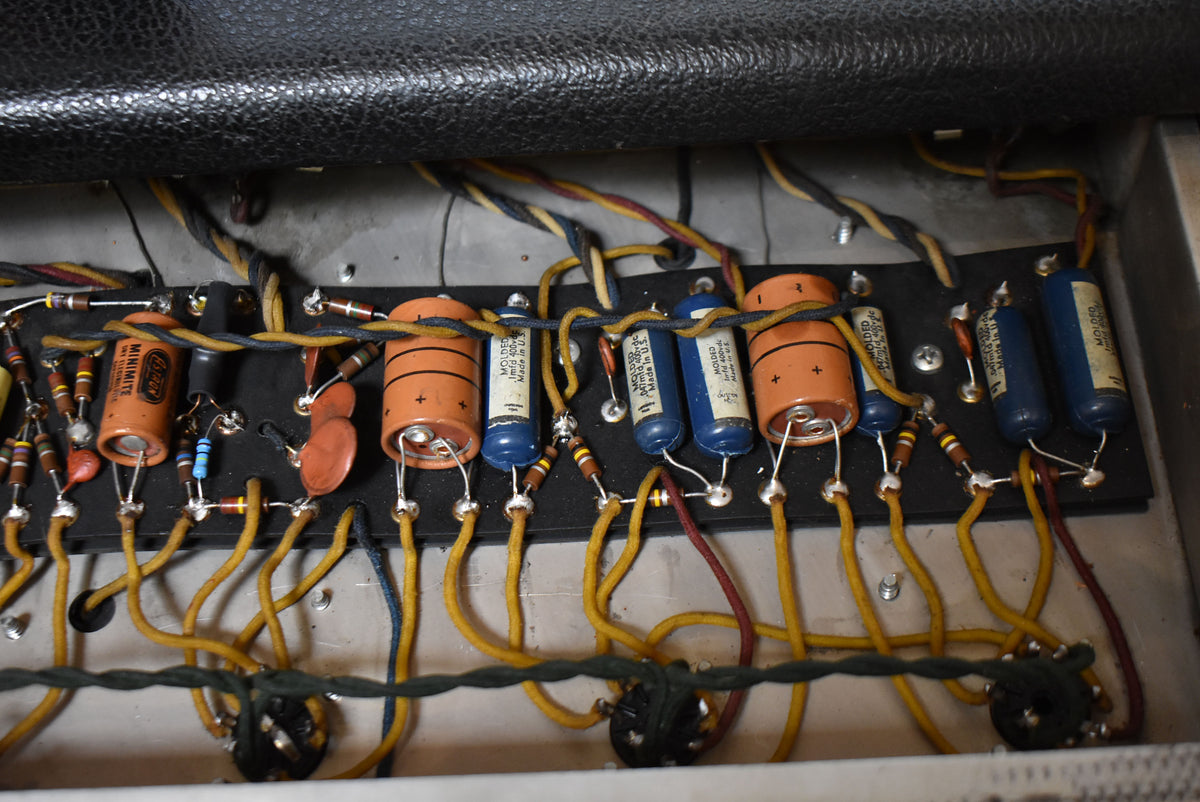 Close-up of the amplifier's internal wiring, showing orange and blue capacitors, resistors, and yellow and black cloth-covered wires.