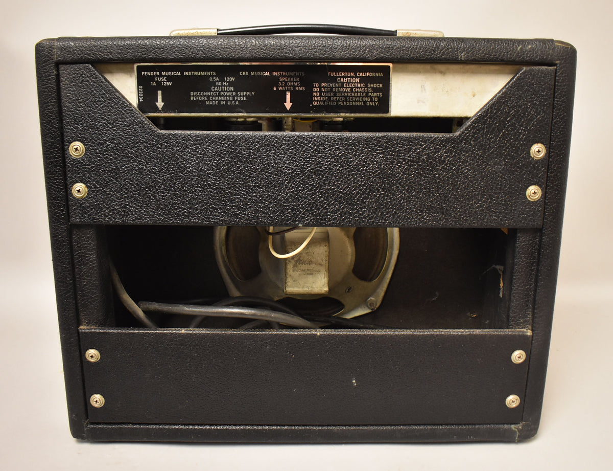 Rear view of the black textured combo amp, showing the open back with a visible speaker and wiring, and a metal control panel.