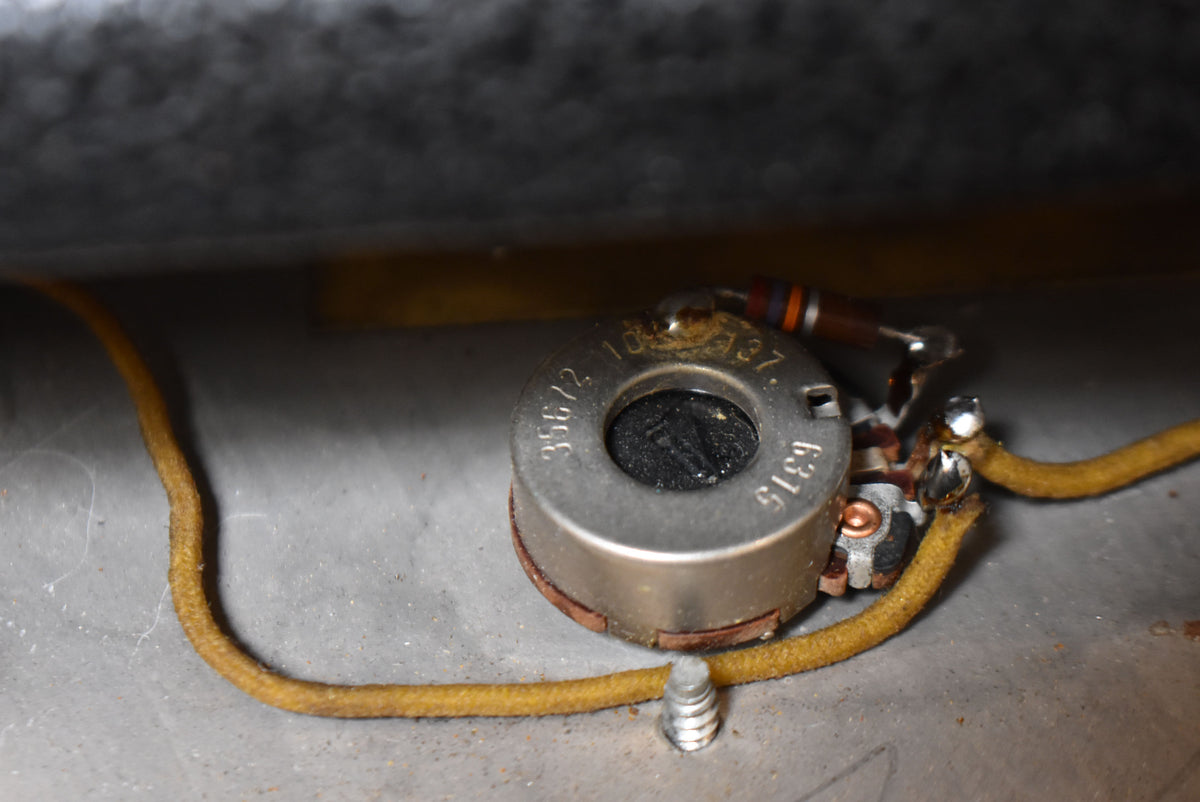 Close-up of the amplifier's internal wiring, showing a silver potentiometer with visible numbers, connected by yellow cloth-covered wires.