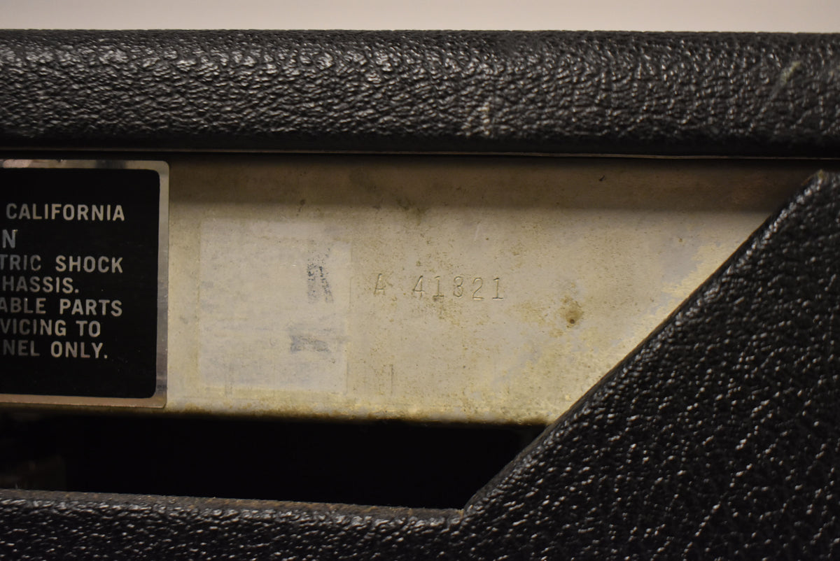 Close-up of the amp's silverface control panel, showing a black warning label and the stamped serial number "A 41821" with some wear.