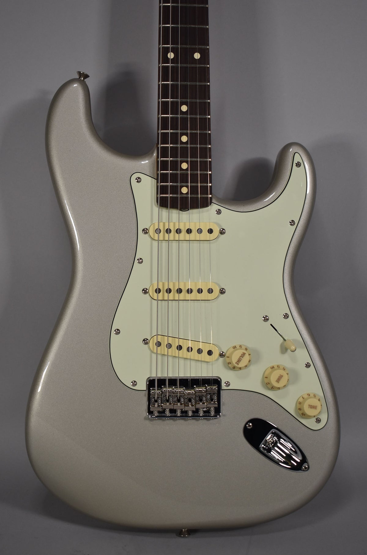 Full front view of a silver Stratocaster with a mint green pickguard, three cream single-coil pickups, and chrome hardware.