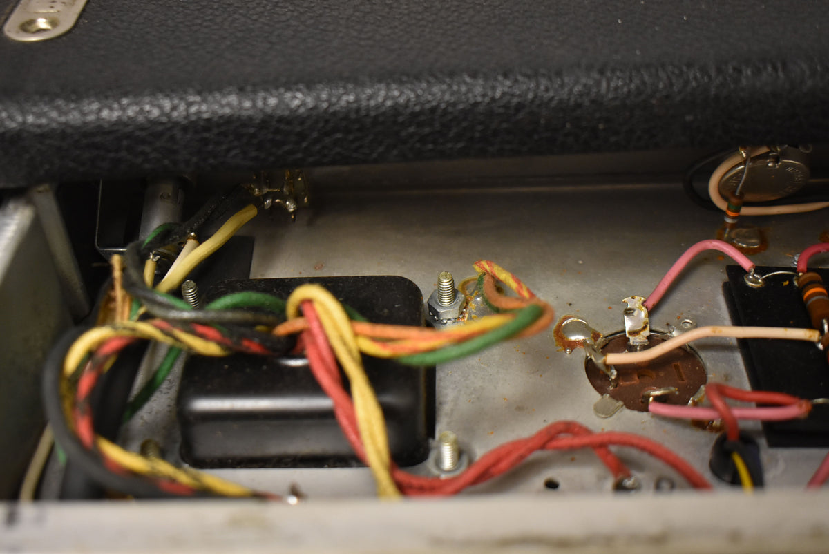 A close-up of the amp's internal wiring, showing colorful wires, solder joints, and components against a silver chassis.