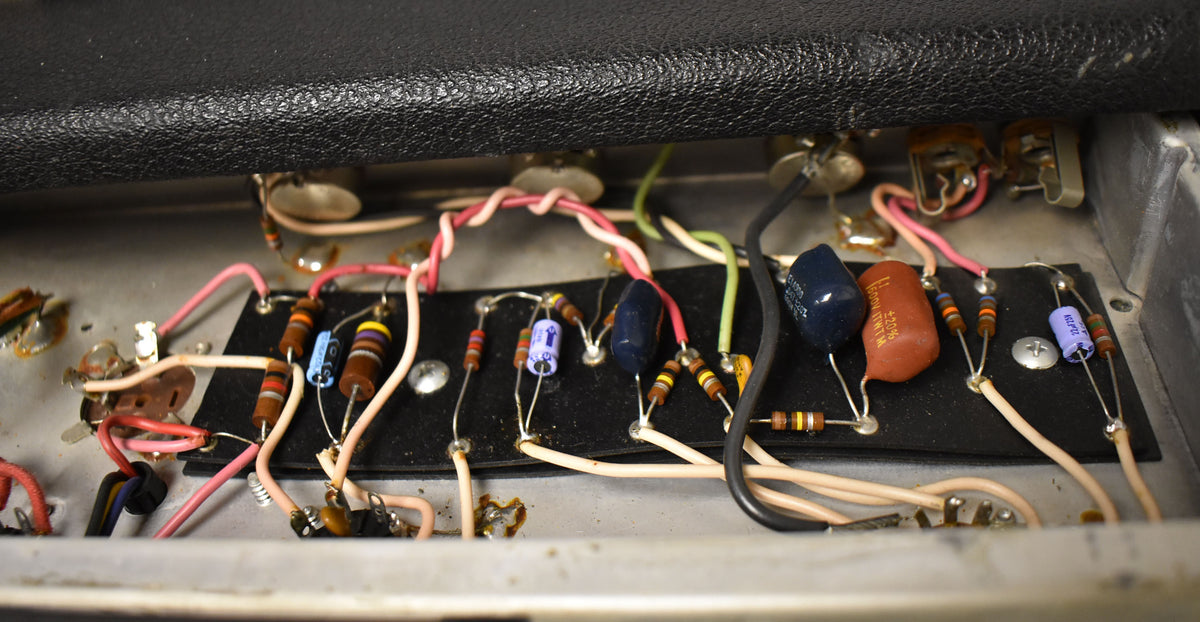 Close-up of the amp's internal wiring, showing various colorful resistors and capacitors on a black board, with some dust.
