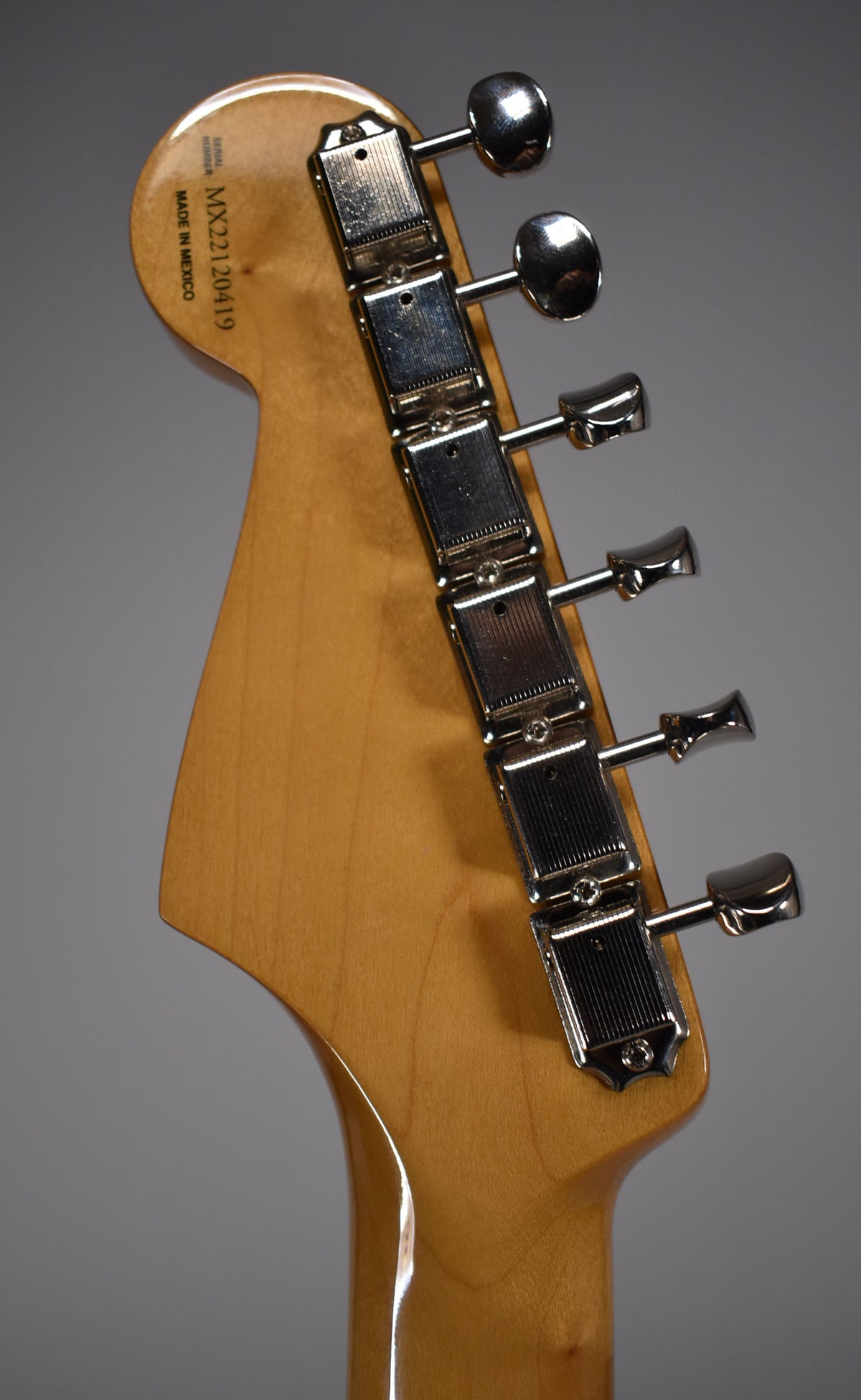 The back of the headstock and top of the neck, showing six chrome tuners and a light wood finish.