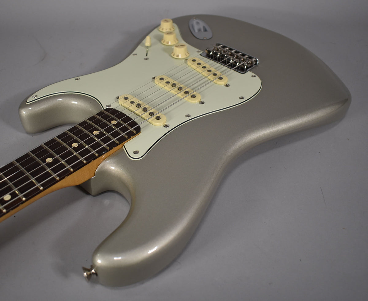 Silver Stratocaster body, angled from the lower bout, showing the light cream pickguard, pickups, and control knobs.