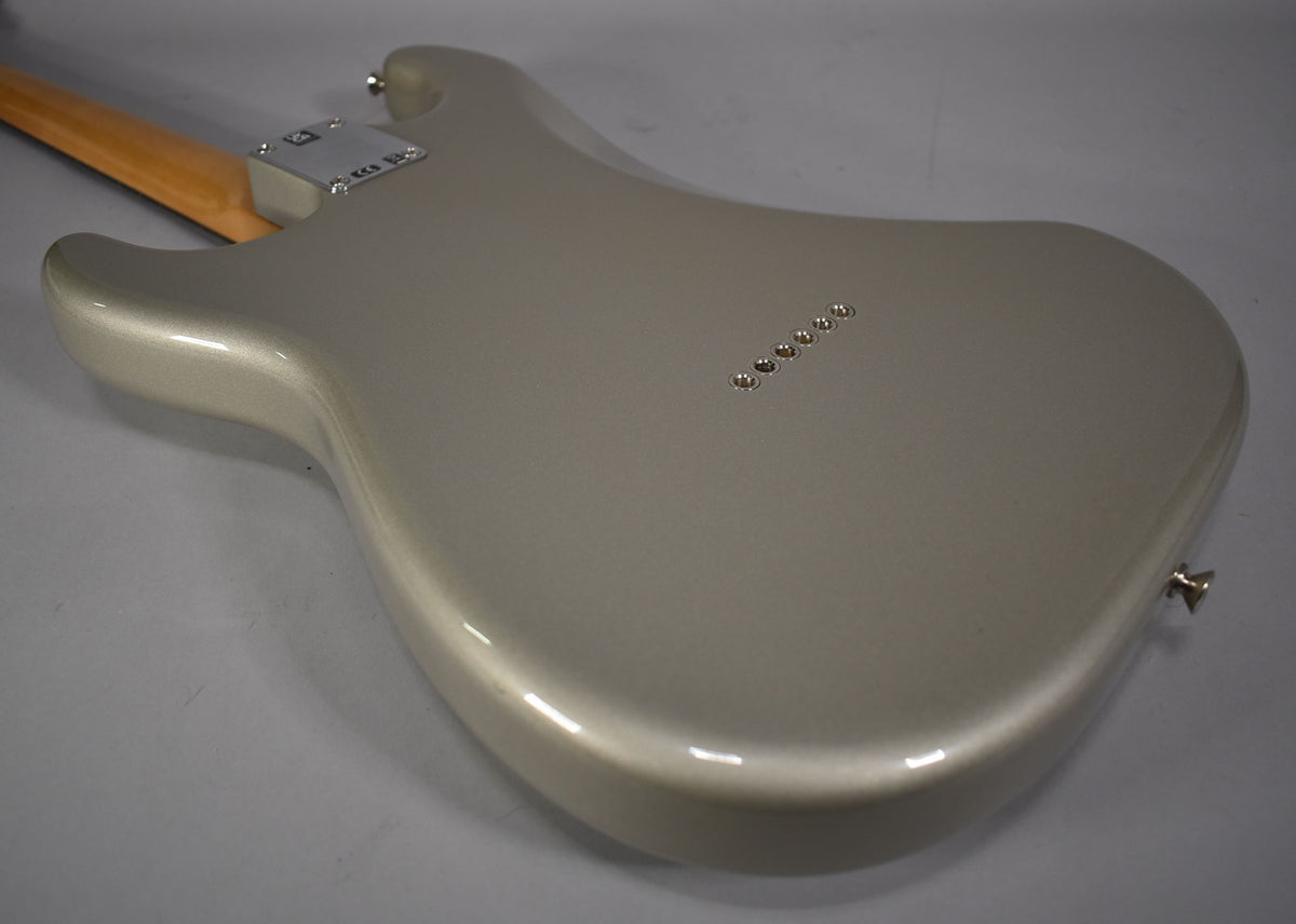 The back of a metallic silver Stratocaster body, showing the neck plate, six string ferrules, and a strap button.