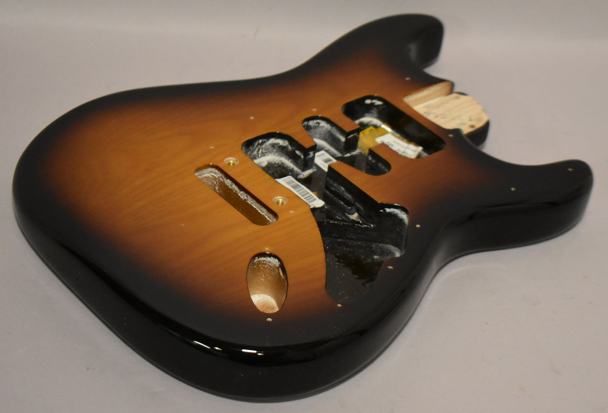 The glossy 2-tone sunburst Stratocaster body is angled, showing the upper bout and routed cavities with some internal wiring.
