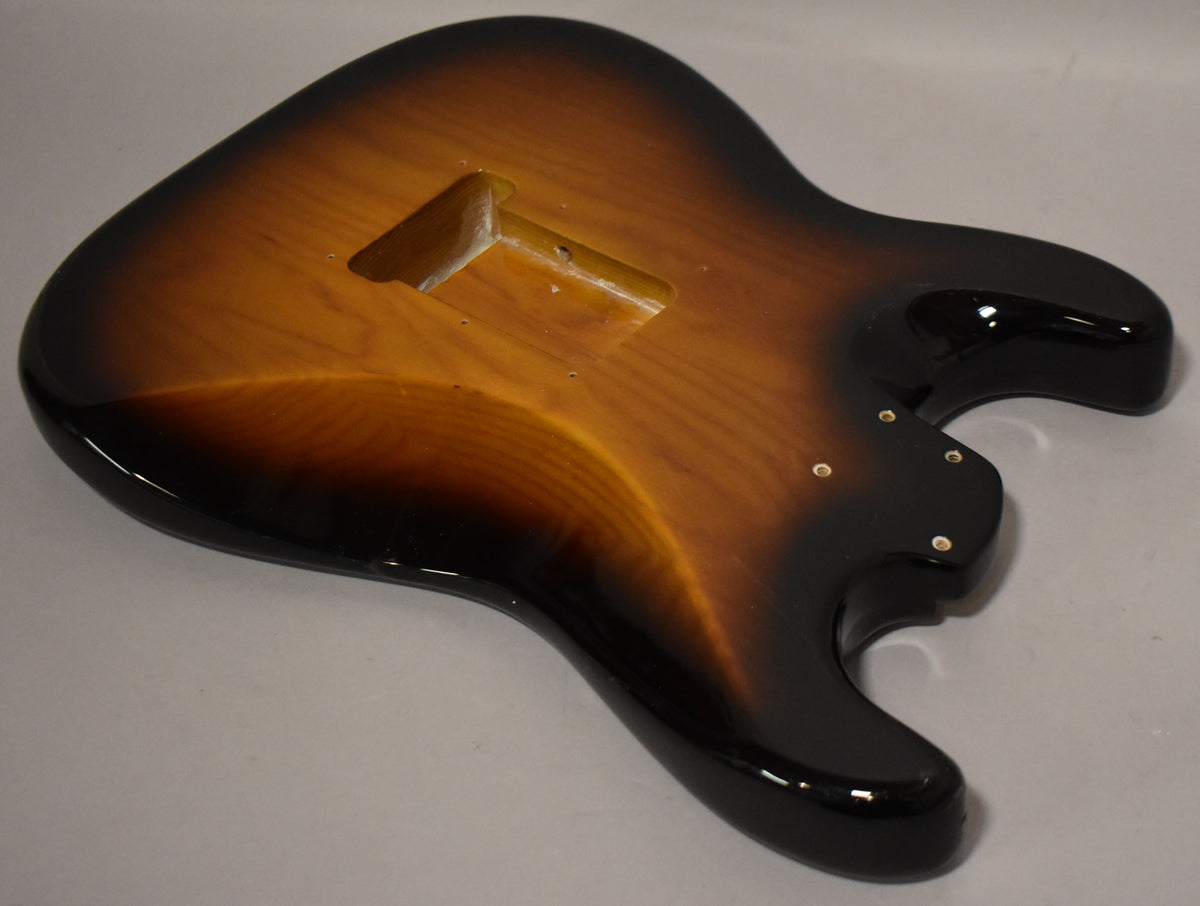 Glossy 2-tone sunburst Stratocaster body, angled from above, showing the bridge cavity and four neck screw holes.