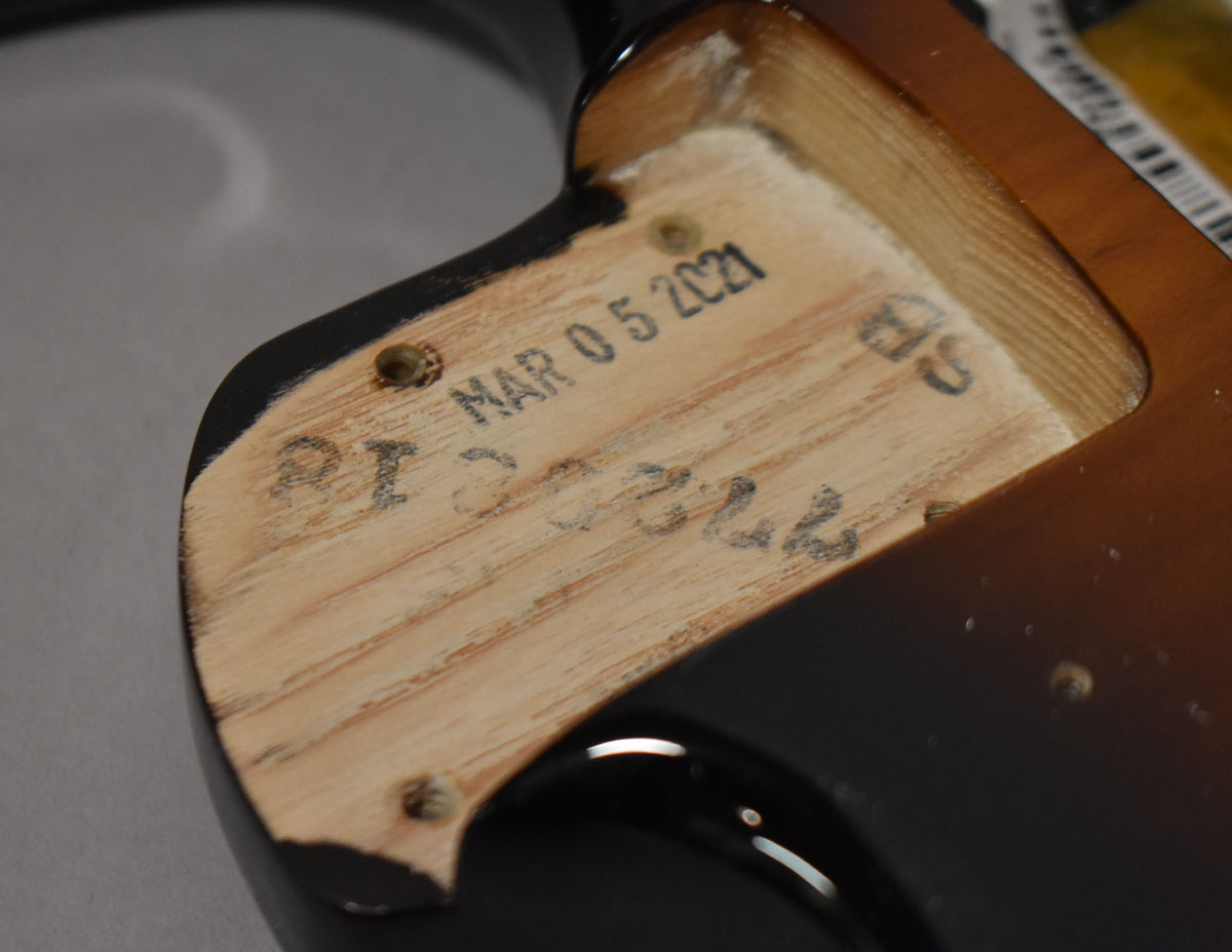 Close-up of the neck pocket of a 2-tone sunburst Stratocaster body, showing stamped date "MAR 05 2021" and other markings.
