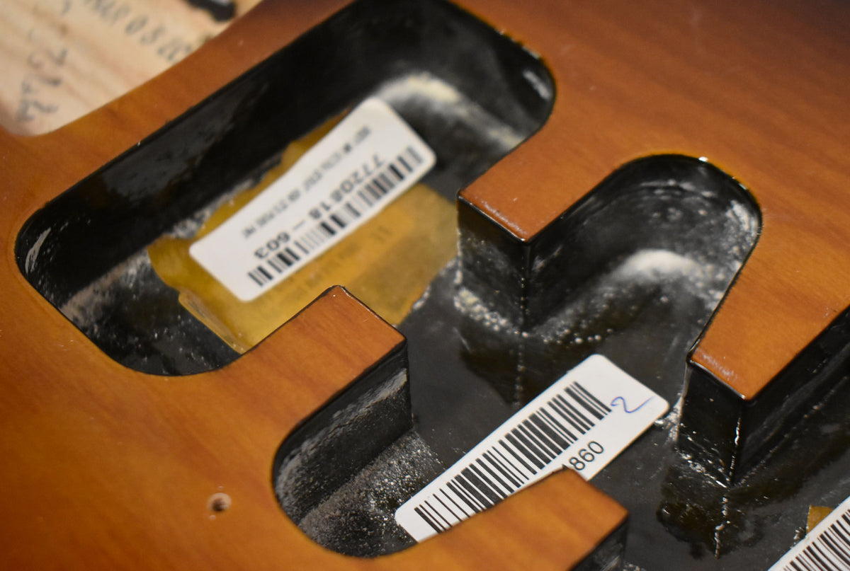 Close-up of the sunburst body's routing cavities, showing two white barcode stickers and some white dust.