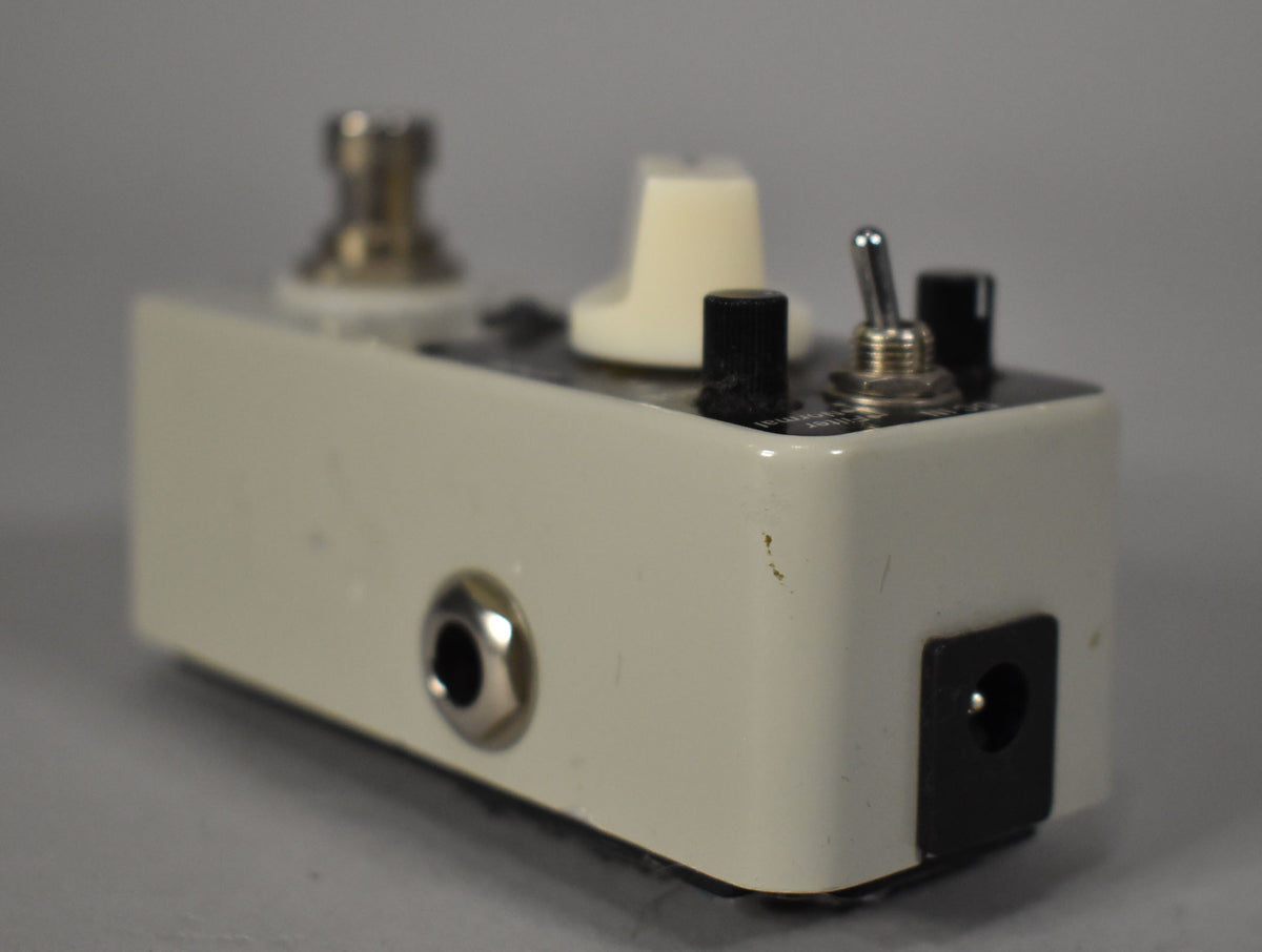 Angled view of the off-white pedal, showing the input jack, power input, and a few small chips in the paint.