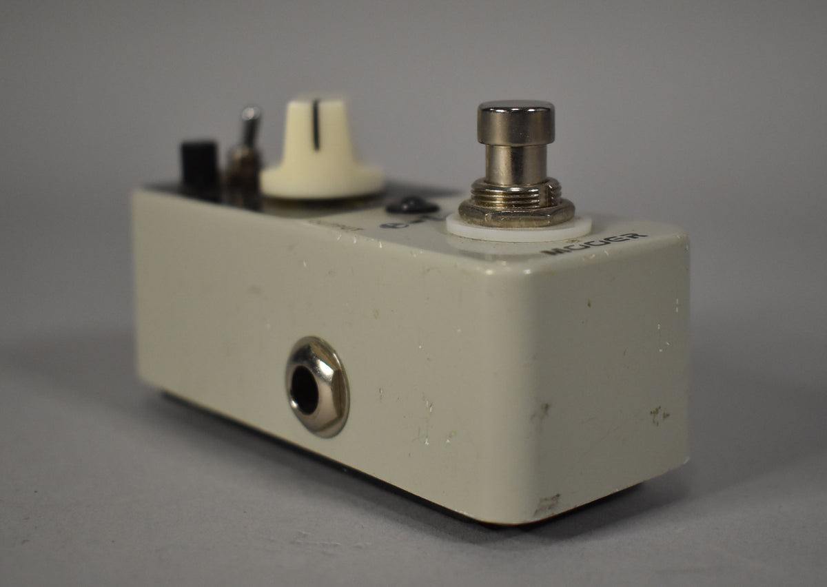 Close-up, low-angle view of the off-white pedal, showing the input jack, footswitch, and a cream knob, with visible scuffs and chips.