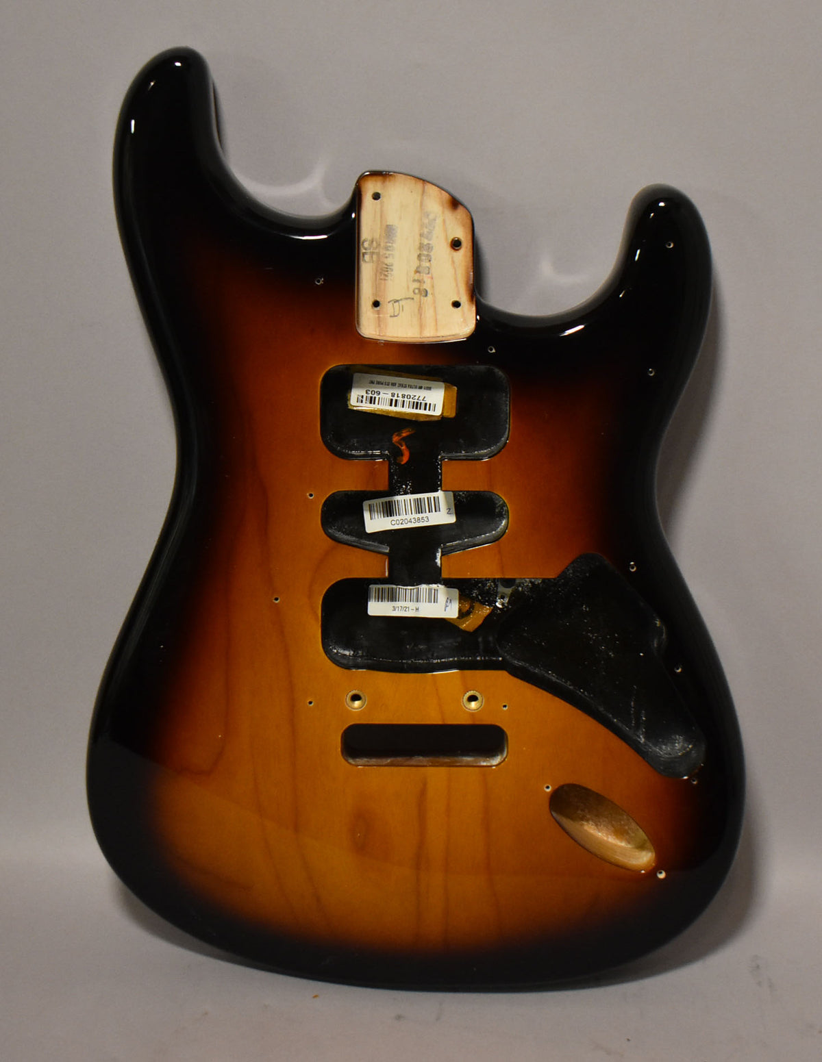 The back of a glossy 2-tone sunburst Stratocaster body, showing the neck pocket, tremolo cavity, and control routes.