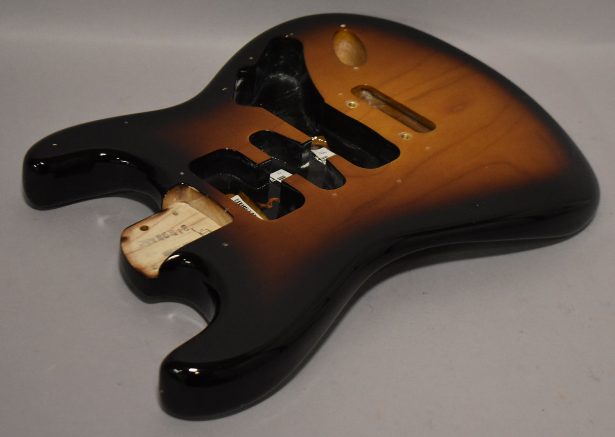 Sunburst Stratocaster body, angled from above, showing the glossy finish, three pickup routes, and the neck pocket.
