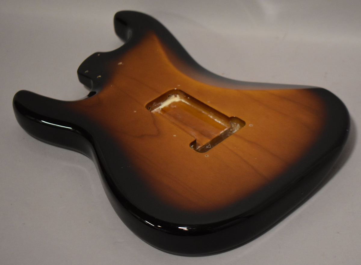 The guitar body, in a glossy 2-tone sunburst, is angled to show the back with a rectangular tremolo cavity and some minor surface wear.