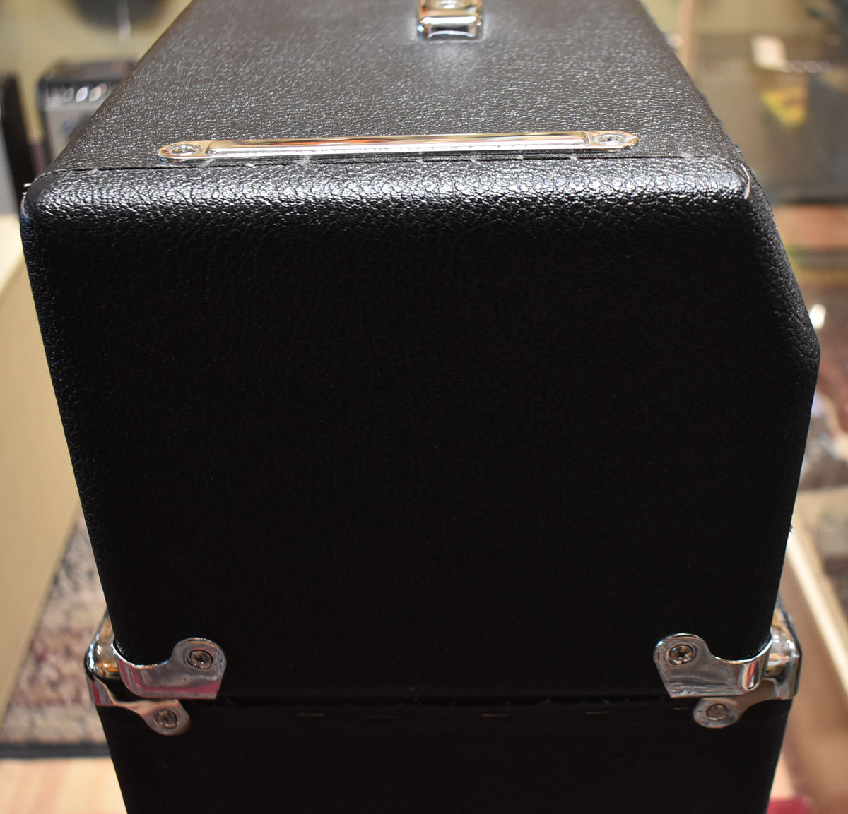Top-down view of the black textured amp head, showing a chrome handle, two chrome side bars, and two chrome corner protectors.