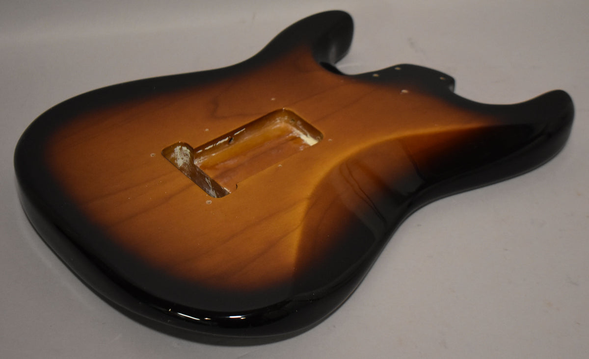 A 2-tone sunburst Stratocaster body, viewed from the back at an angle, showing the tremolo cavity and some wear inside.