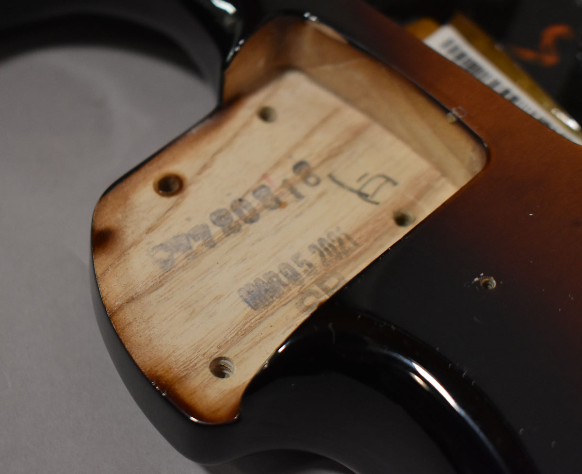 Close-up of the neck pocket on a glossy 2-tone sunburst Stratocaster body, showing wood grain and stamped numbers.