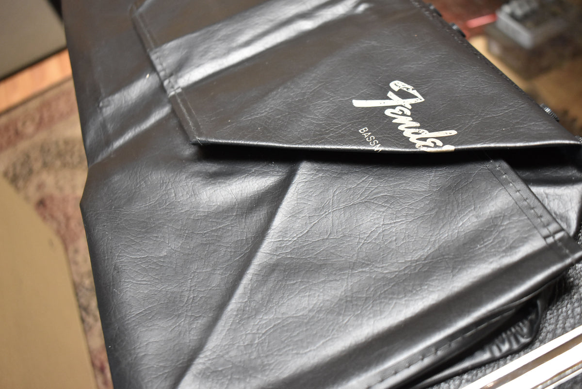 A black vinyl cover with a white script logo partially covers the amp, showing some creasing and light wear.