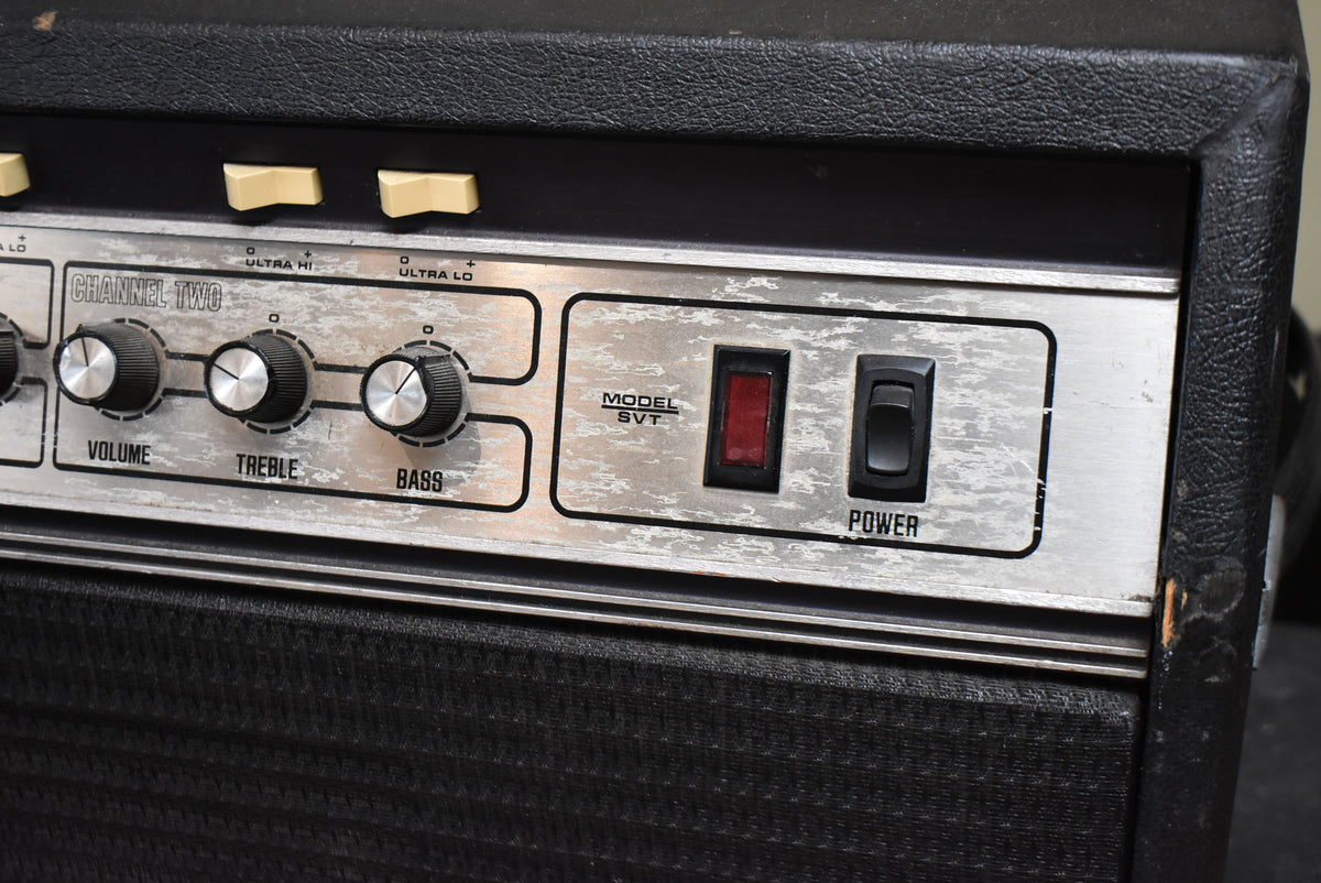 Close-up of the amp's silver control panel with three black knobs, a red indicator light, and a black power switch, showing wear.
