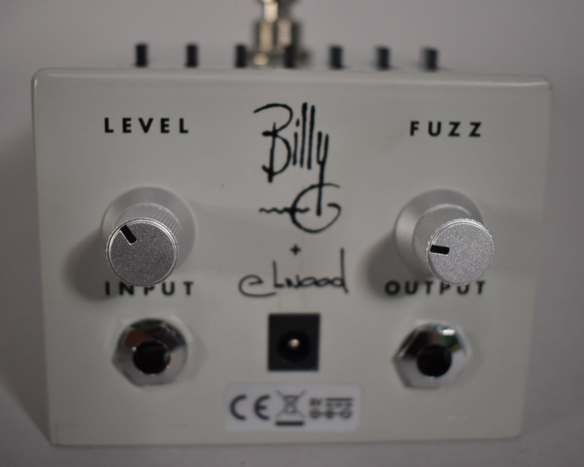 The off-white pedal is viewed from the front, showing two silver knurled control knobs, input/output jacks, and a power input.