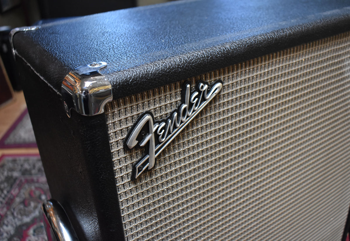 Close-up of the amp's upper right corner, showing black textured tolex, a silver grille cloth, and a chrome corner protector.