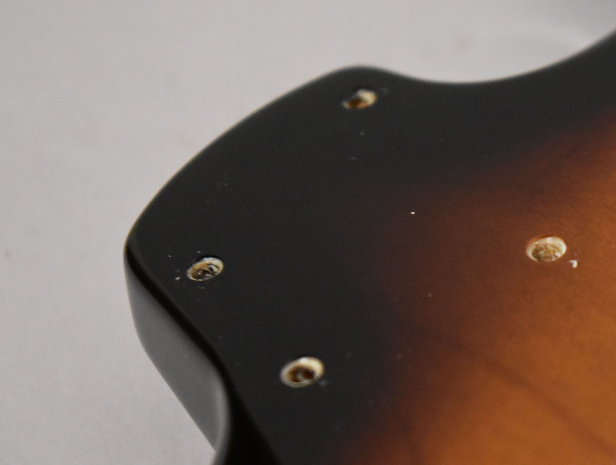 Close-up of the upper horn of a glossy 2-tone sunburst body, showing four neck screw holes and light surface dust.