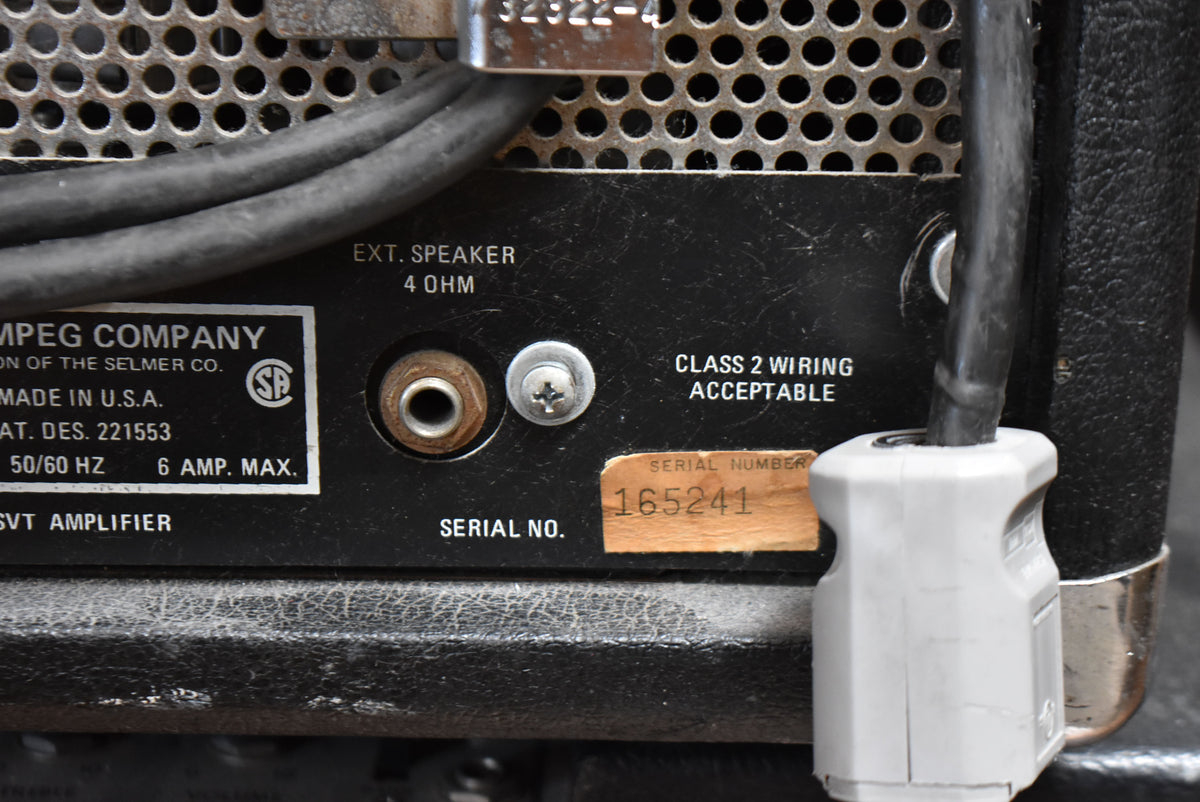 Close-up of the amp's rear panel, showing the "EXT. SPEAKER 4 OHM" jack, a serial number sticker, and a power cable.