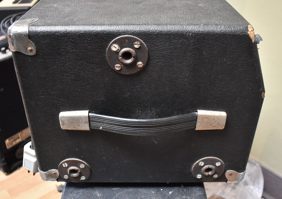The black tolex-covered amp head's side shows a carry handle, metal corner protectors, and four circular feet, with some wear and tears.