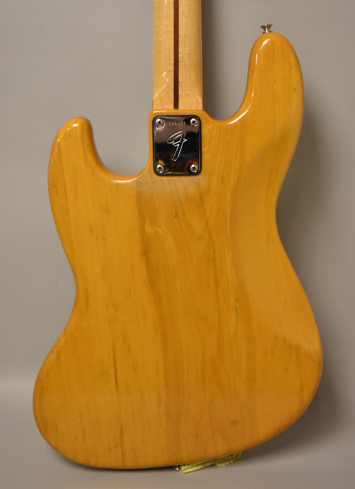 Rear view of the natural finish bass body, showing the neck plate, a few small dings, and wood grain.