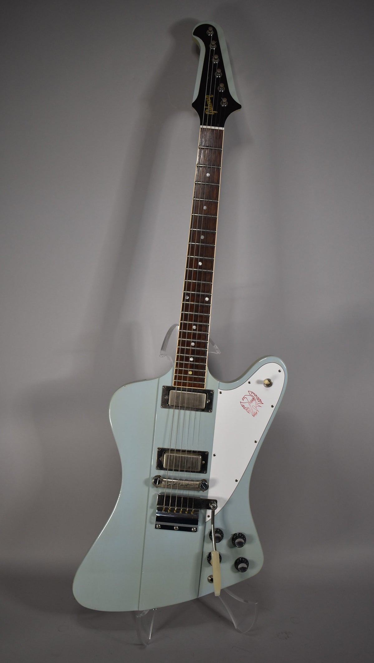 Full view of a light blue electric guitar with a white pickguard featuring a red bird graphic, chrome hardware, and a tremolo arm.