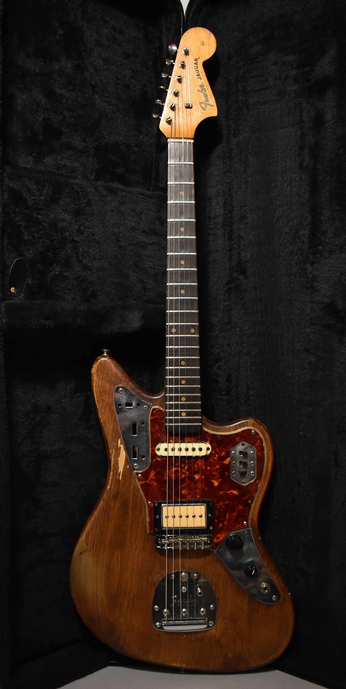 Full-length view of a natural wood guitar with a tortoiseshell pickguard, a cream humbucker, and significant finish wear.