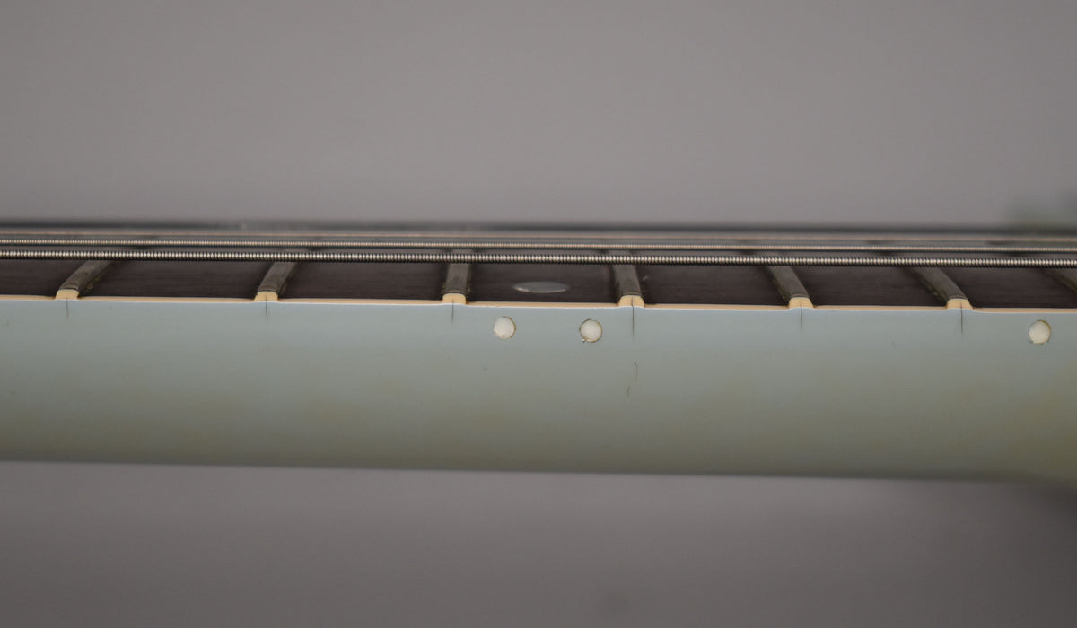 Close-up of the guitar's light blue neck binding and dark fretboard, showing side dot markers and light fret wear.