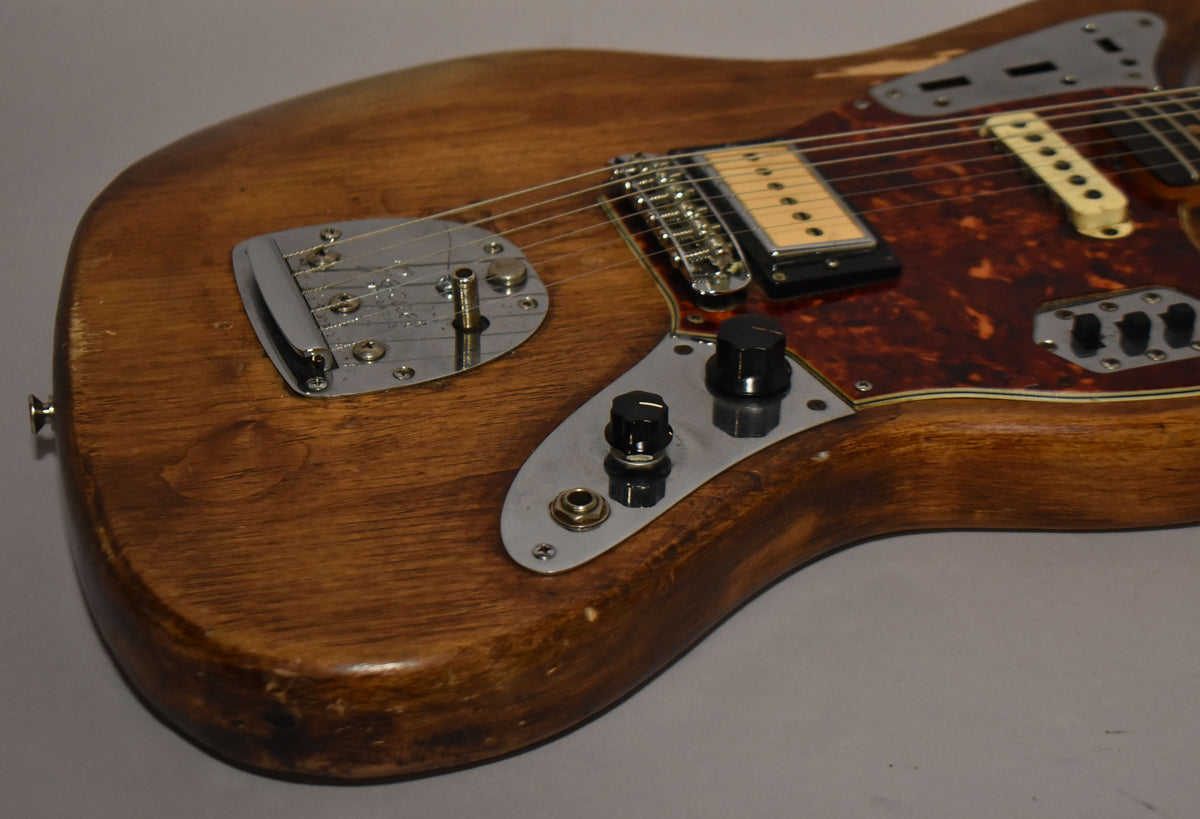 Close-up of the lower body, showing the natural wood finish, chrome vibrato, tortoise pickguard, and two black control knobs.