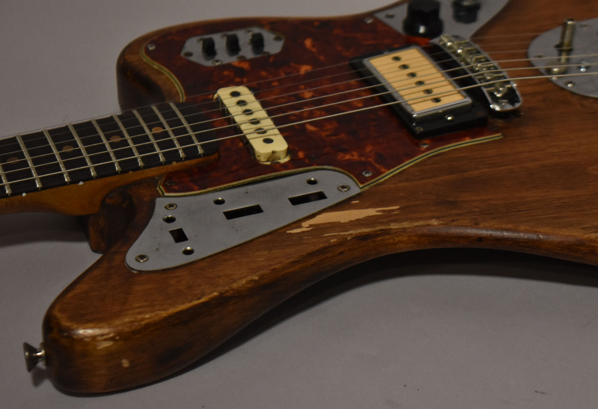 Close-up of a natural wood guitar body with a tortoiseshell pickguard, showing significant finish wear and a humbucker bridge pickup.