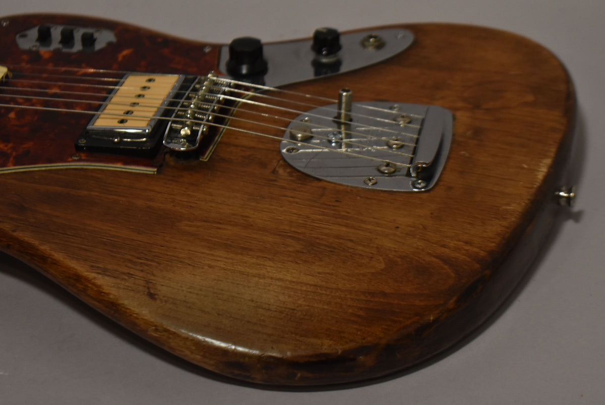 Close-up of a natural wood guitar body with a tortoiseshell pickguard, chrome bridge, and a cream-colored single-coil pickup.