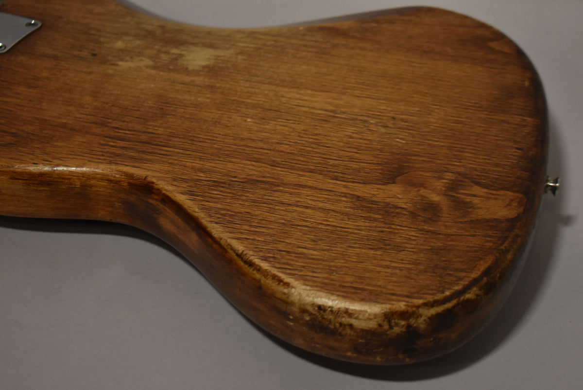 Close-up of the guitar's lower back, showing a natural wood finish with visible grain, wear, and a strap button on the lower bout.