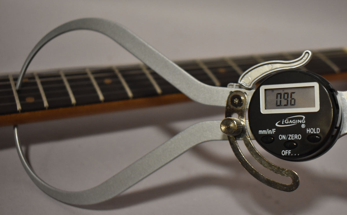 A digital caliper measures the fret height at 0.96mm on the dark rosewood fretboard with light rectangular inlays.