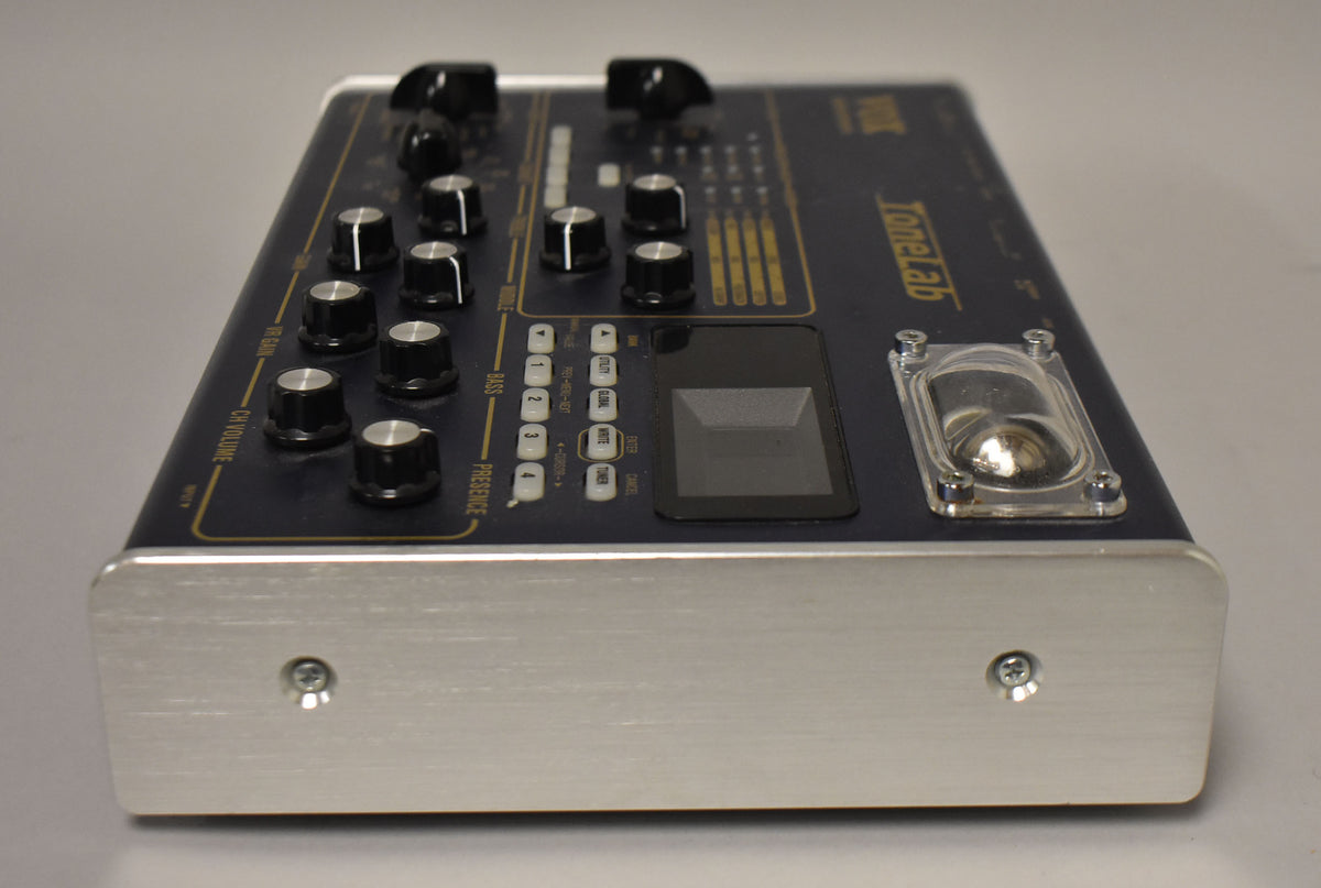 The blue pedal is angled right, showing its brushed aluminum side, black knobs, white buttons, screen, and a clear tube cover.