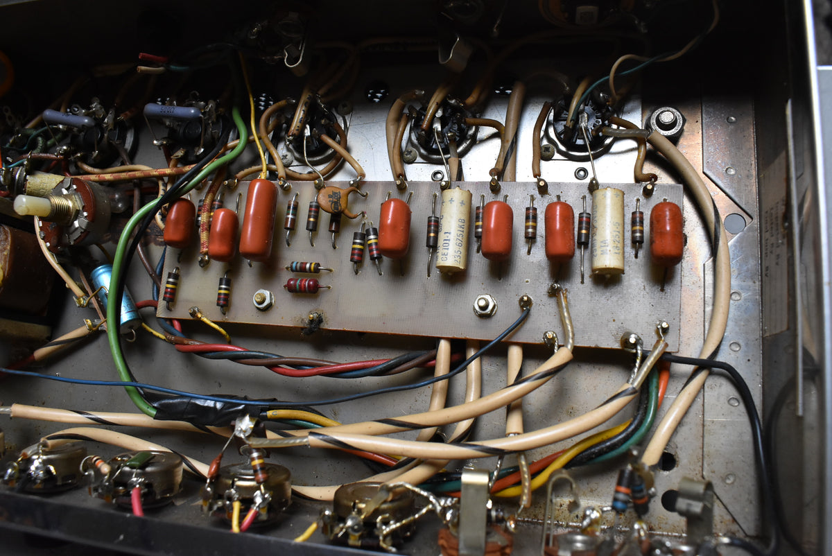 Close-up of the amp's internal wiring, showing a circuit board with orange and cream capacitors, resistors, and colorful wires.