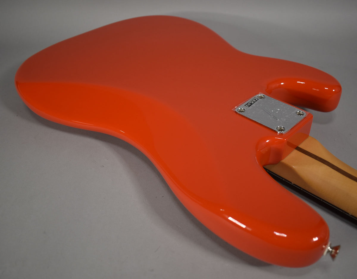 The back of a glossy coral red bass body, angled from the lower bout to the neck joint with a chrome neck plate.