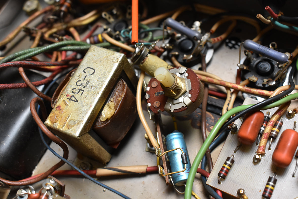 Close-up of the amp's internal wiring, showing a tarnished gold transformer, a light blue capacitor, and several orange resistors.