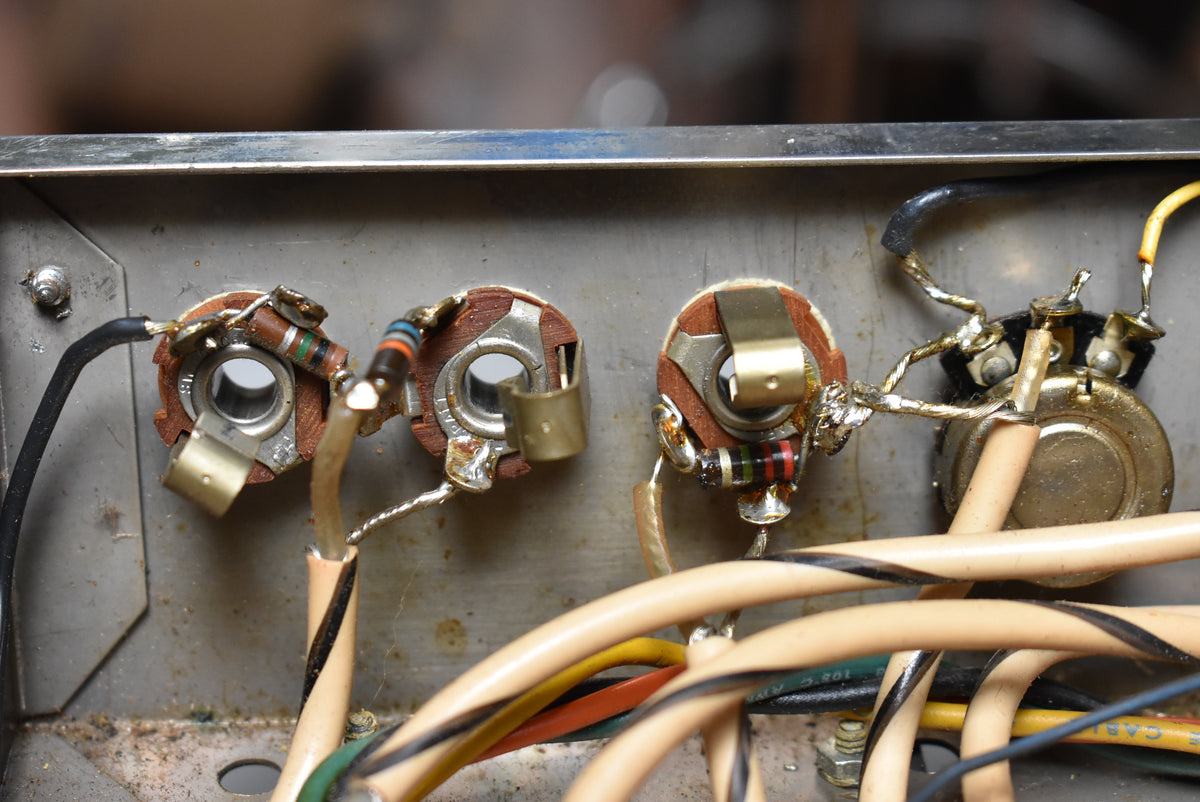 Close-up of the amp's internal wiring, showing three input jacks, resistors, and a potentiometer with various colored wires.