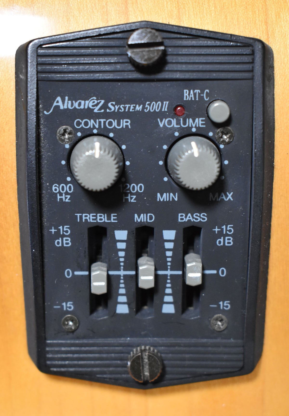 Close-up of the black preamp control panel with two grey rotary knobs, three grey slider controls, and a red LED, mounted on light wood.