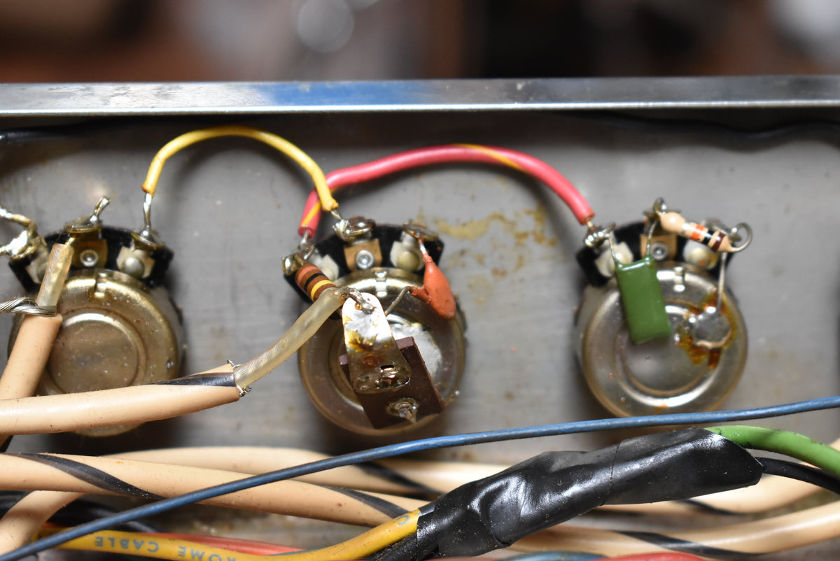Close-up of three tarnished potentiometers with colorful wiring, resistors, and capacitors, showing solder joints and some rust.